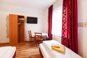 a hotel room with two beds and a table and chairs at Pension Jasmin in Pforzheim