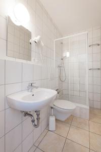 a white bathroom with a sink and a toilet at Pension Jasmin in Pforzheim