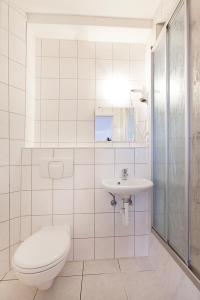 Baño blanco con aseo y lavamanos en Pension Jasmin, en Pforzheim