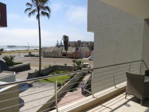 a balcony with a view of the beach and a palm tree at Spoil Yourself in Swakopmund