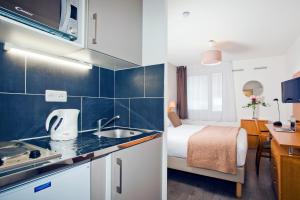 a small kitchen with a bed in a hotel room at Séjours & Affaires Pantin Charles De Gaulle in Pantin