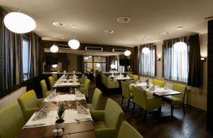 un restaurant avec des tables, des chaises jaunes et des lumières dans l'établissement Konsumhotel Oberhof - Berghotel Oberhof, à Oberhof