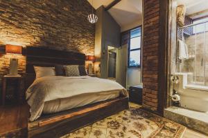 a bedroom with a bed and a brick wall at The Cow Hollow Hotel in Manchester