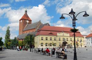 a building with a clock tower and people sitting on benches at Apartamenty Amon z widokiem na morze in Darlowko +18 photos