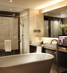 a bathroom with a tub and a tv in it at Joy Nostalg Hotel and Suites Manila Managed by The Ascott Limited in Manila