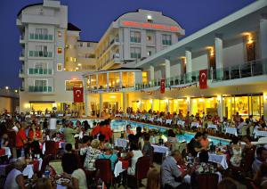 a large group of people sitting at tables in front of a building at Merve Sun Hotel & SPA in Side