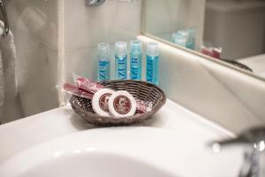 - Cesta de cepillos de dientes y pasta de dientes en el lavabo del baño en Hotel Concordy, en Madrid