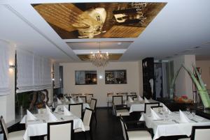 ein Esszimmer mit weißen Tischen und Stühlen und einer Decke in der Unterkunft Hotel Hamann in Balingen