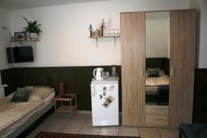 a room with a refrigerator and a bed and a mirror at Fontana Vendégház in Tát