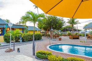 uma piscina de resort com guarda-sol, mesas e cadeiras em MVC Eagle Beach em Palm-Eagle Beach