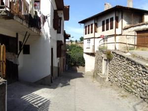 Une allée avec deux bâtiments et un mur en pierre dans l'établissement Efe Guest House, à Safranbolu