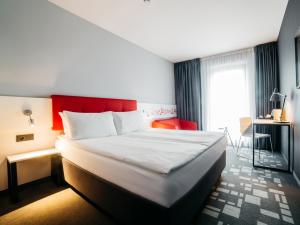 a hotel room with a bed and a red headboard at Q Hotel Kraków in Krakow