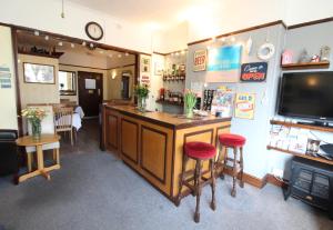 a bar in a restaurant with two stools and a tv at Maluth Lodge in Great Yarmouth