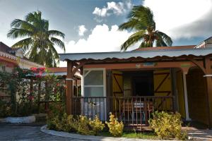 a house with a porch and palm trees in the background at Village Honoré in Saint-François