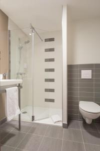 a bathroom with a shower and a toilet and a sink at Akena City Reims Bezannes in Reims