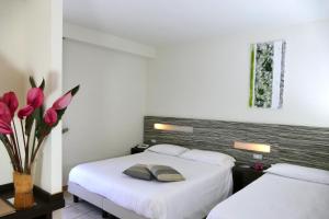 two beds in a room with two pink tulips at Hotel Village Scoglio Della Galea in Capo Vaticano