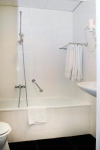 a white bathroom with a tub and a sink at Amrâth Hotel Eindhoven in Eindhoven