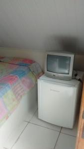 a tv sitting on top of a dresser next to a bed at Chalézinhos São Roque in São Roque