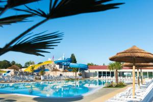 a pool at a resort with chairs and umbrellas at Mobile Home 701 in Les Mathes