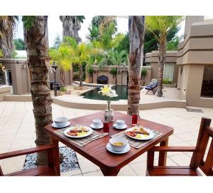 una mesa de madera con dos platos de comida. en Oudtshoorn Guest House en Oudtshoorn