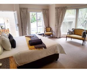 a bedroom with a large bed and two chairs at Oudtshoorn Guest House in Oudtshoorn