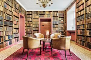 a library with a table and chairs and bookshelves at Ny Øbjerggaard Bed and Breakfast in Lundby