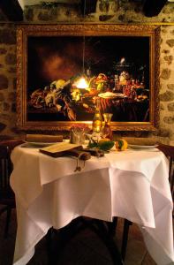 une table avec un chiffon de table blanc et une peinture dans l'établissement Hotel Restaurant des Deux Rocs, à Seillans