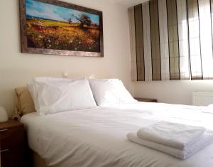 a bedroom with a white bed with a painting on the wall at Elvita Athens Sea View Maisonette in Athens