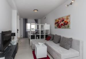 a white living room with a couch and a tv at Apartments Luna in Dubrovnik