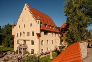 um grande edifício branco com um telhado vermelho em Ferienwohnung Schlossberg em Hopferau