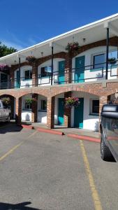 a brick building with flowers on the balconies in a parking lot at Schell Motel in Vernon