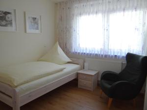 a bedroom with a bed and a chair and a window at Villa Sonnenhof in Bad Steben