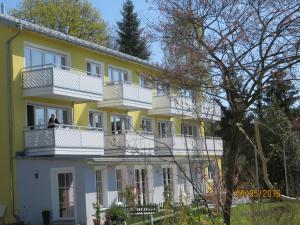um homem de pé na varanda de um edifício amarelo e branco em Villa Sonnenhof em Bad Steben