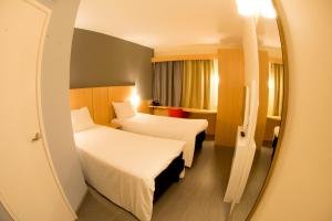 Habitación de hotel con 2 camas y espejo en ibis Aracruz, en Aracruz