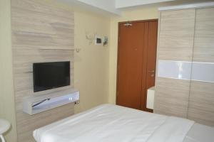 Schlafzimmer mit einem Bett und einem Flachbild-TV in der Unterkunft Green Lake View - Tower E 59 Acuan Laundry Time in Pondokcabe Hilir