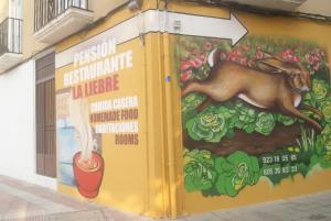 a mural on the side of a building with a painting of a dog at Pensión Restaurante La Liebre in Salamanca