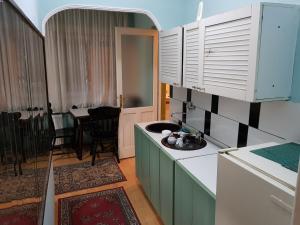 a kitchen with green cabinets and a dining room at Hostel Mimi in Leskovac