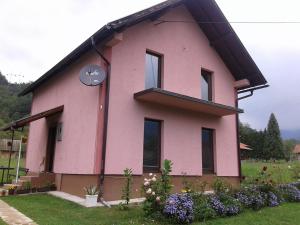 una casa rosa con techo negro en Rooms Violeta en Mokra Gora
