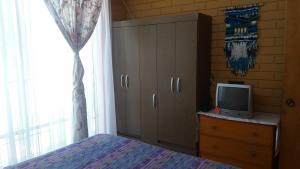 1 dormitorio con cama y vestidor con TV en Hostal Los Nogales, en Coquimbo