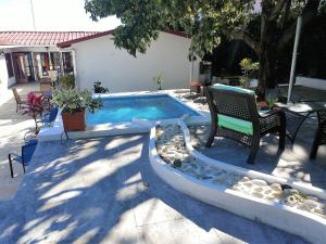 a pool with two chairs and a table and a bench at El Mirador Suites and Lounge in Managua