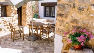 eine Terrasse mit einem Tisch, Stühlen und Blumen in der Unterkunft Casas Rurales Tio Frasquito y Cleto in Yeste