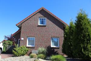 a red brick house with two windows on it at Das GrachtenDOMiZiL Greetsiel in Greetsiel