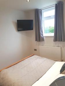 ein Schlafzimmer mit einem Bett mit einem Flachbildfernseher an der Wand in der Unterkunft The Studio in Ingoldmells