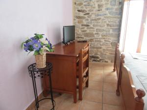 una camera da letto con una scrivania con una televisione e fiori di Hotel rural Valtarranz a Noceco