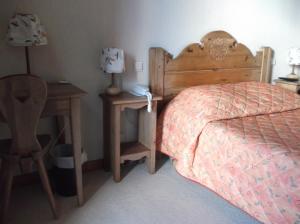 ein Schlafzimmer mit einem Bett, einem Nachttisch und einem Tisch in der Unterkunft Hôtel Les Mottets in Aussois
