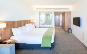 een hotelkamer met een groot bed en een televisie bij Commodore Airport Hotel Christchurch in Christchurch