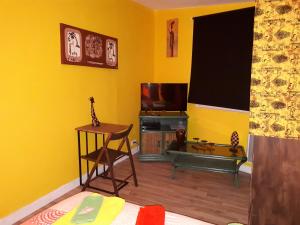 sala de estar con paredes amarillas y TV en Chez Patricia & Denis, en Flassans-sur-Issole