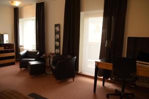 a living room with chairs and a desk and a television at Landhotel Röfleuten in Pfronten