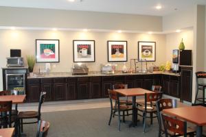 um restaurante com mesas e uma cozinha com quadros na parede em Brookstone Lodge & Suites - Emmetsburg em Emmetsburg