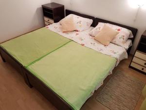 a bedroom with a bed with green sheets and pillows at Apartments Polic with Terrace in Baška